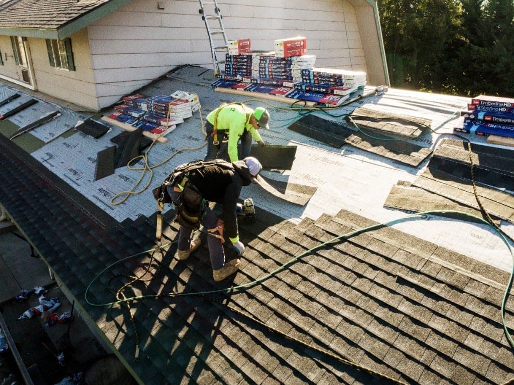 Eminent Roofing crew installing asphalt shingles in bright sun