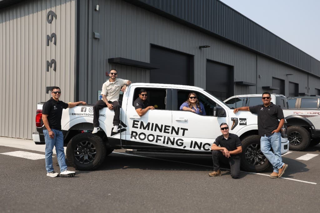 Eminent Roofing team posed with a branded company truck at the Richland shop